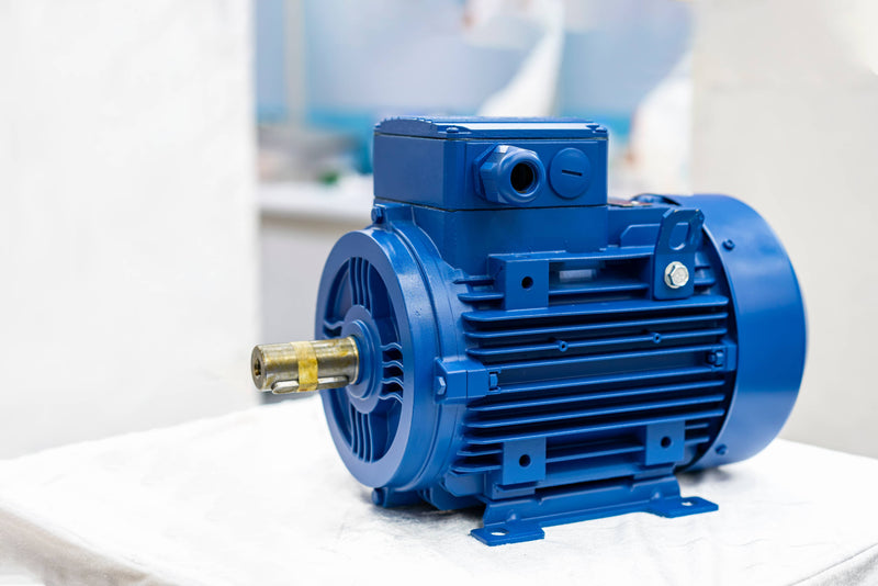 Blue electric motor on a white surface with a blurred background